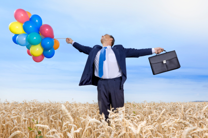 Businessman in wheat field with briefcase and balloons